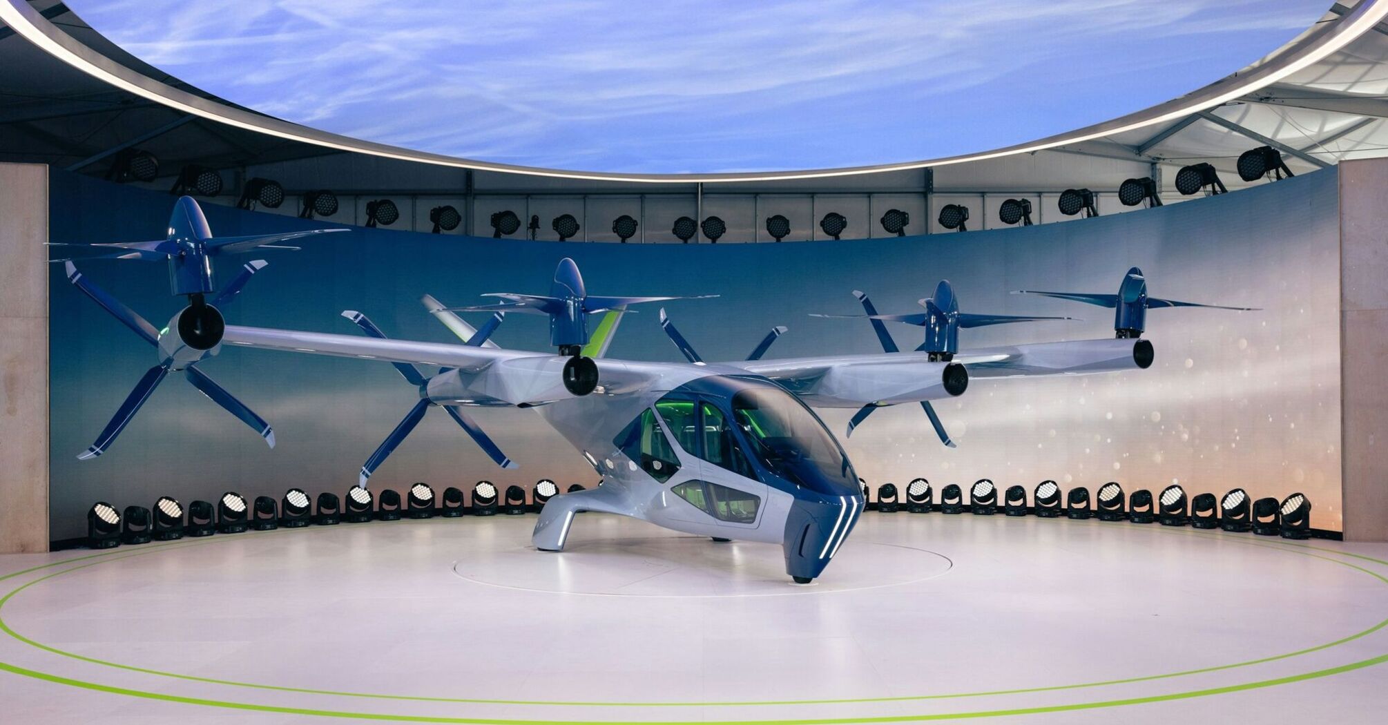 A futuristic electric air taxi with six rotors displayed in an exhibition setting