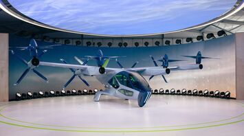 A futuristic electric air taxi with six rotors displayed in an exhibition setting