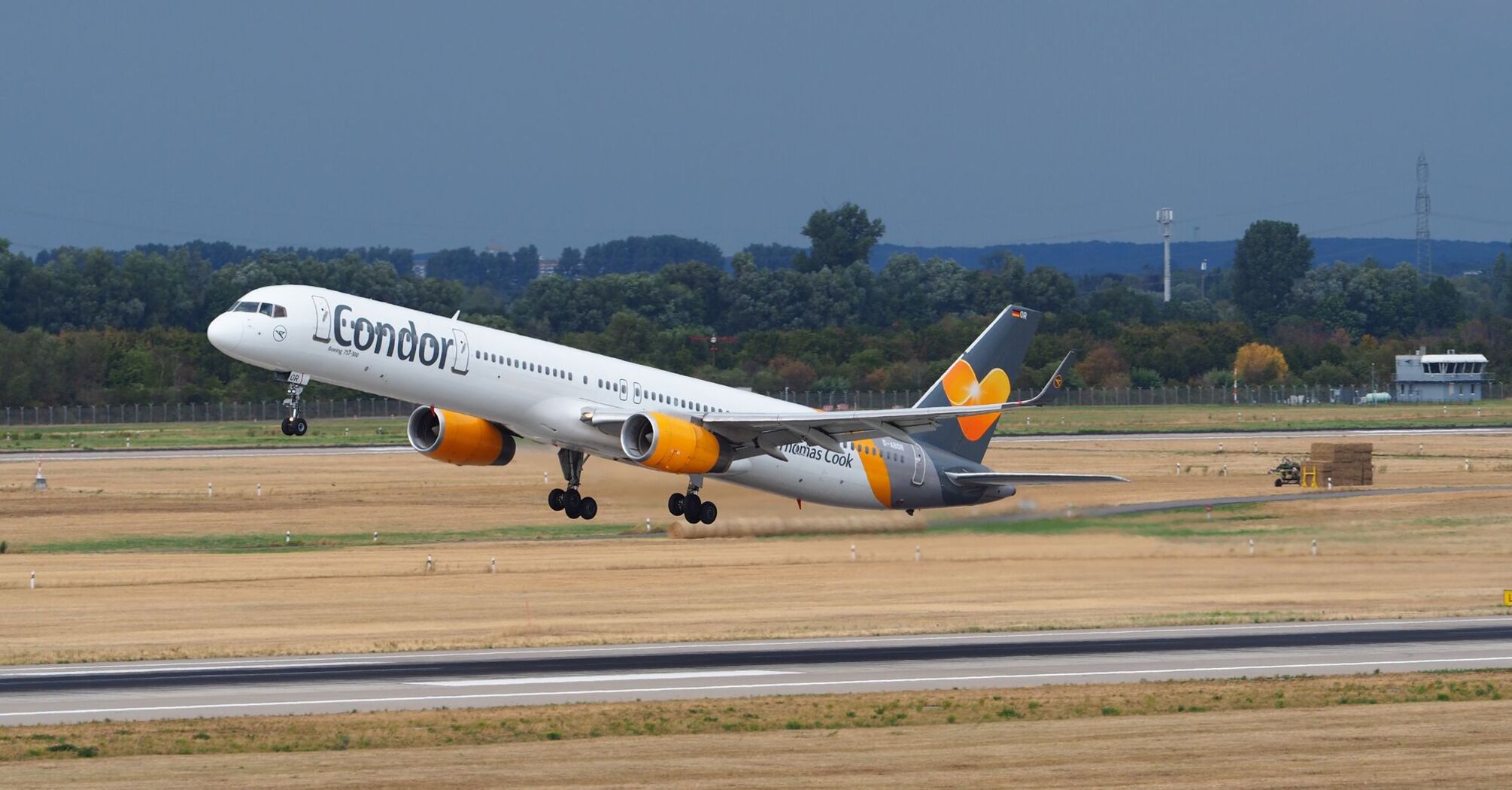 A Condor aircraft taking off from a runway under a cloudy sky