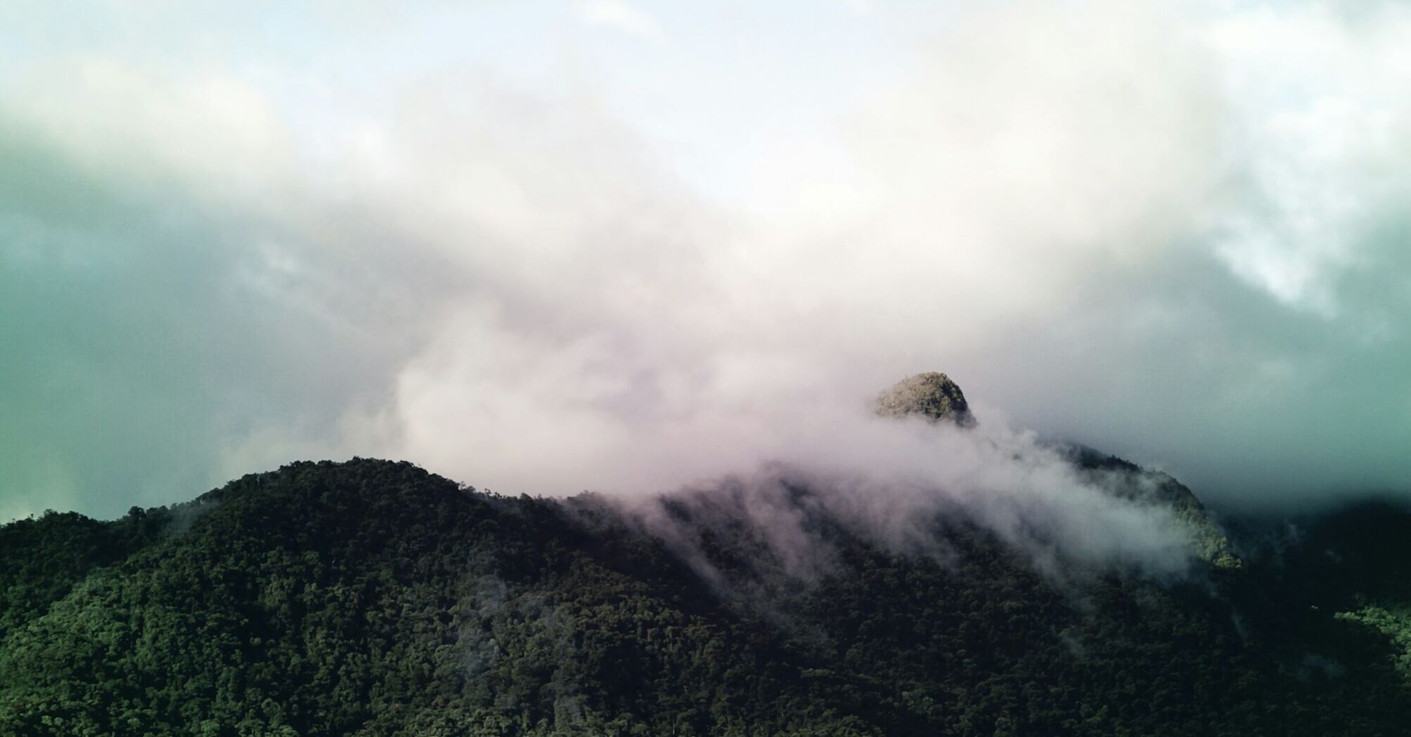 Cloud-covered green mountains with mist rolling over