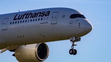 Lufthansa Airbus A350-900 landing with extended landing gear against a clear blue sky