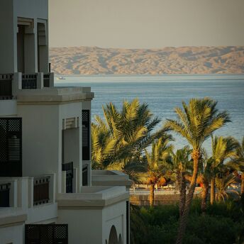 A seaside resort in Hurghada, Egypt, with palm trees and a view of the Red Sea and distant mountains in the background