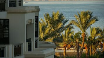 A seaside resort in Hurghada, Egypt, with palm trees and a view of the Red Sea and distant mountains in the background