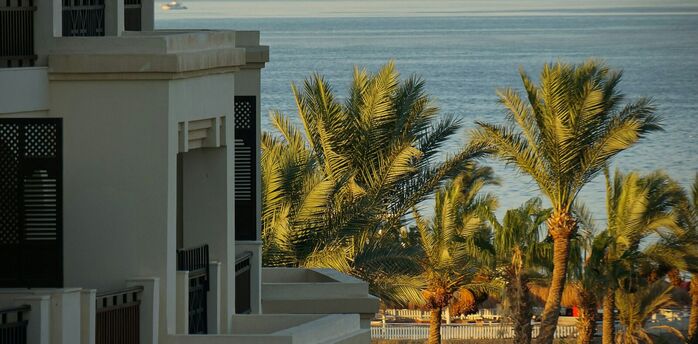 A seaside resort in Hurghada, Egypt, with palm trees and a view of the Red Sea and distant mountains in the background