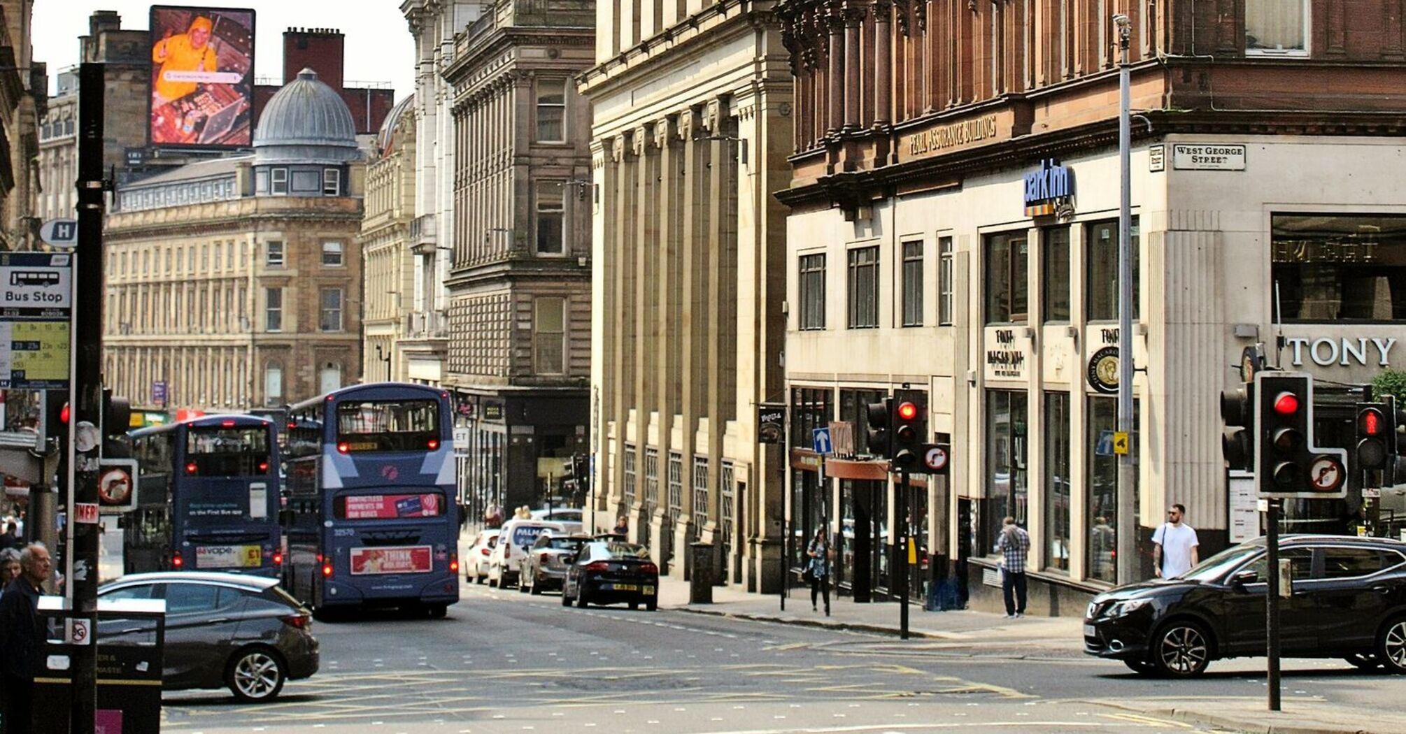 Busy Glasgow street with double-decker First Bus buses and historic architecture