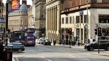 Busy Glasgow street with double-decker First Bus buses and historic architecture