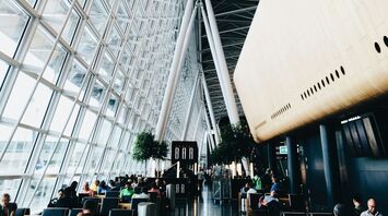 Spacious interior of Zurich Airport terminal with passengers seated near large glass windows