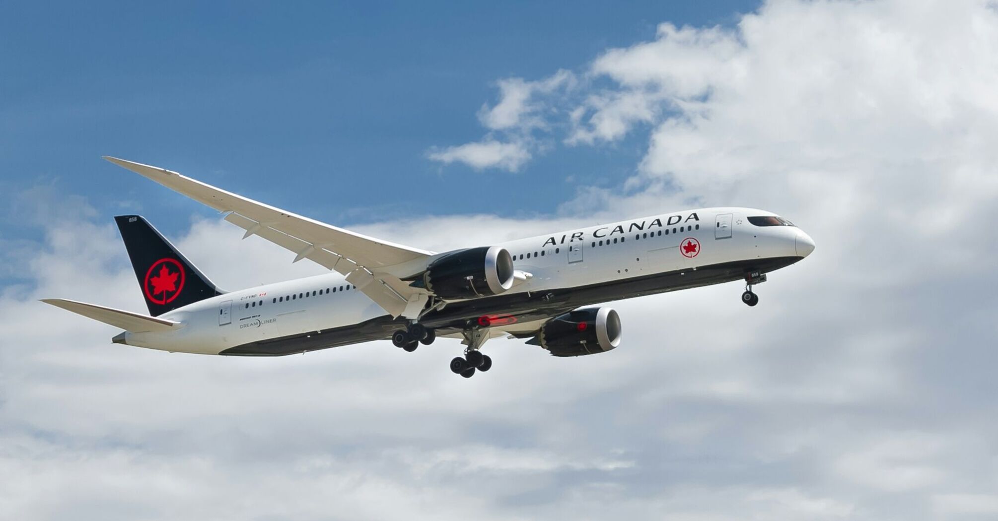 Air Canada aircraft in flight against a partly cloudy sky