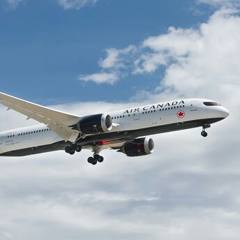 Air Canada aircraft in flight against a partly cloudy sky