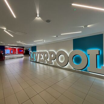 Interior of Liverpool John Lennon Airport with illuminated Liverpool sign and currency exchange area
