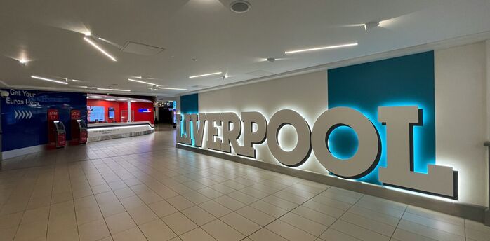Interior of Liverpool John Lennon Airport with illuminated Liverpool sign and currency exchange area