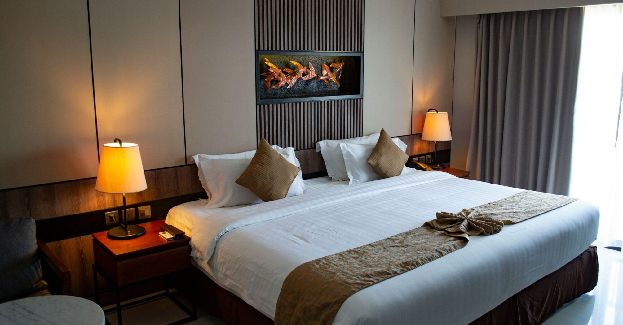 Modern hotel room with ambient lighting, large bed, and neutral décor