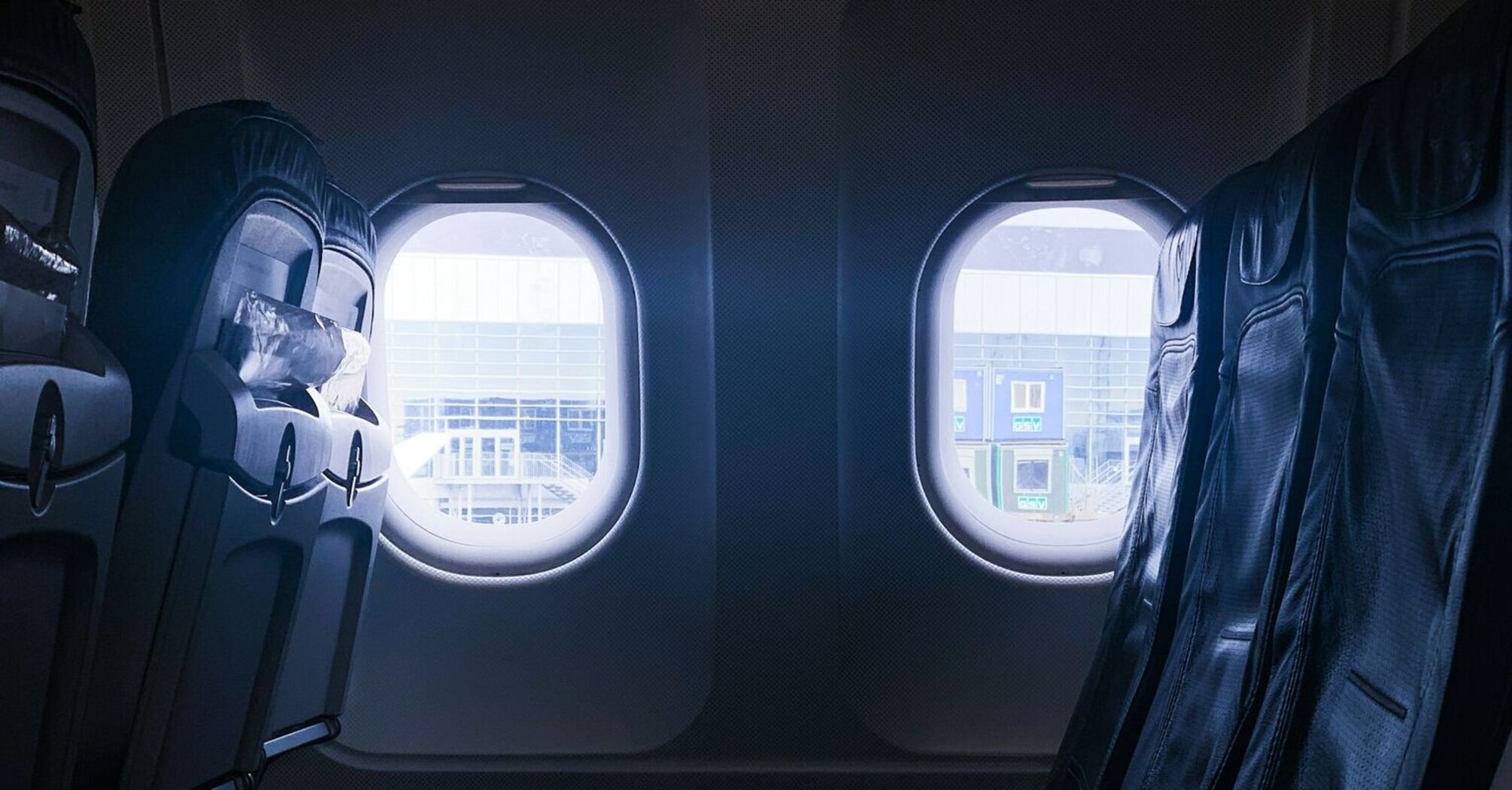 Empty row of airplane seats next to windows at an airport gate