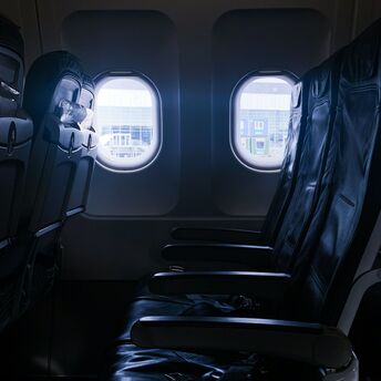 Empty row of airplane seats next to windows at an airport gate