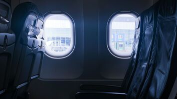 Empty row of airplane seats next to windows at an airport gate