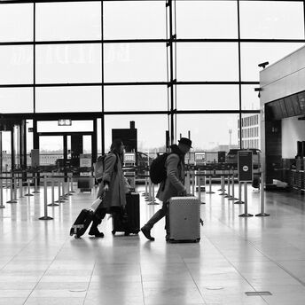 Travelers pulling luggage through a nearly empty airport check-in area
