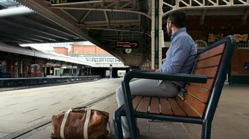 Man waiting at Nottingham Train Station with a travel bag
