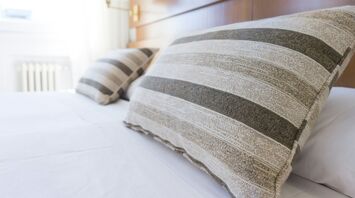 Striped pillows on a neatly made hotel bed in a bright, modern room