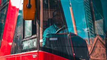 Bus driver inside a red city bus on a sunny day