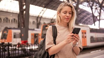 Young woman using smartphone at a European train station