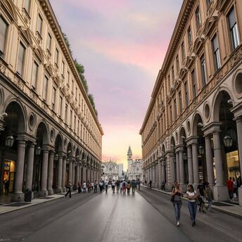 People walking along a historic street in central Torino at sunset