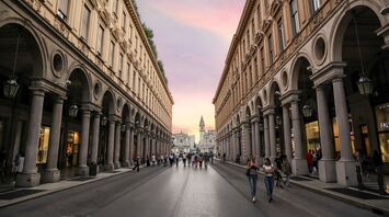 People walking along a historic street in central Torino at sunset