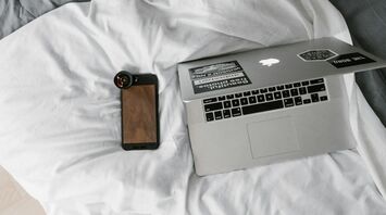 Laptop and smartphone on a hotel bed