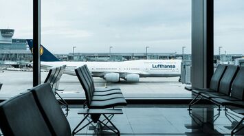 Lufthansa aircraft at airport gate viewed from empty terminal seating area