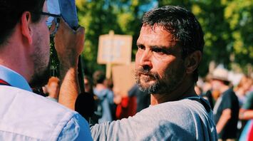 Man participating in a public protest or demonstration, facing another person in conversation