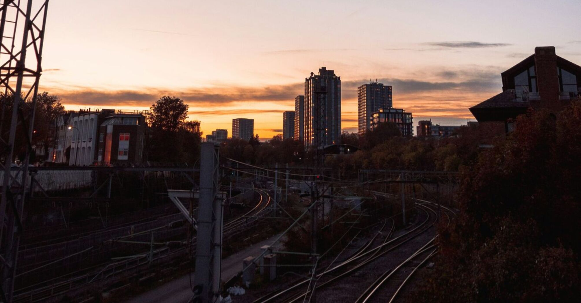 A railway at sunset with city buildings in the background, showing an urban transportation network