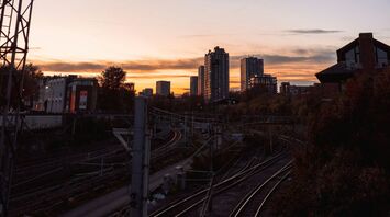 A railway at sunset with city buildings in the background, showing an urban transportation network