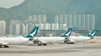 Cathay airplanes parked at Hong Kong International Airport with city skyline in background