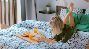 Woman enjoying breakfast in hotel bed