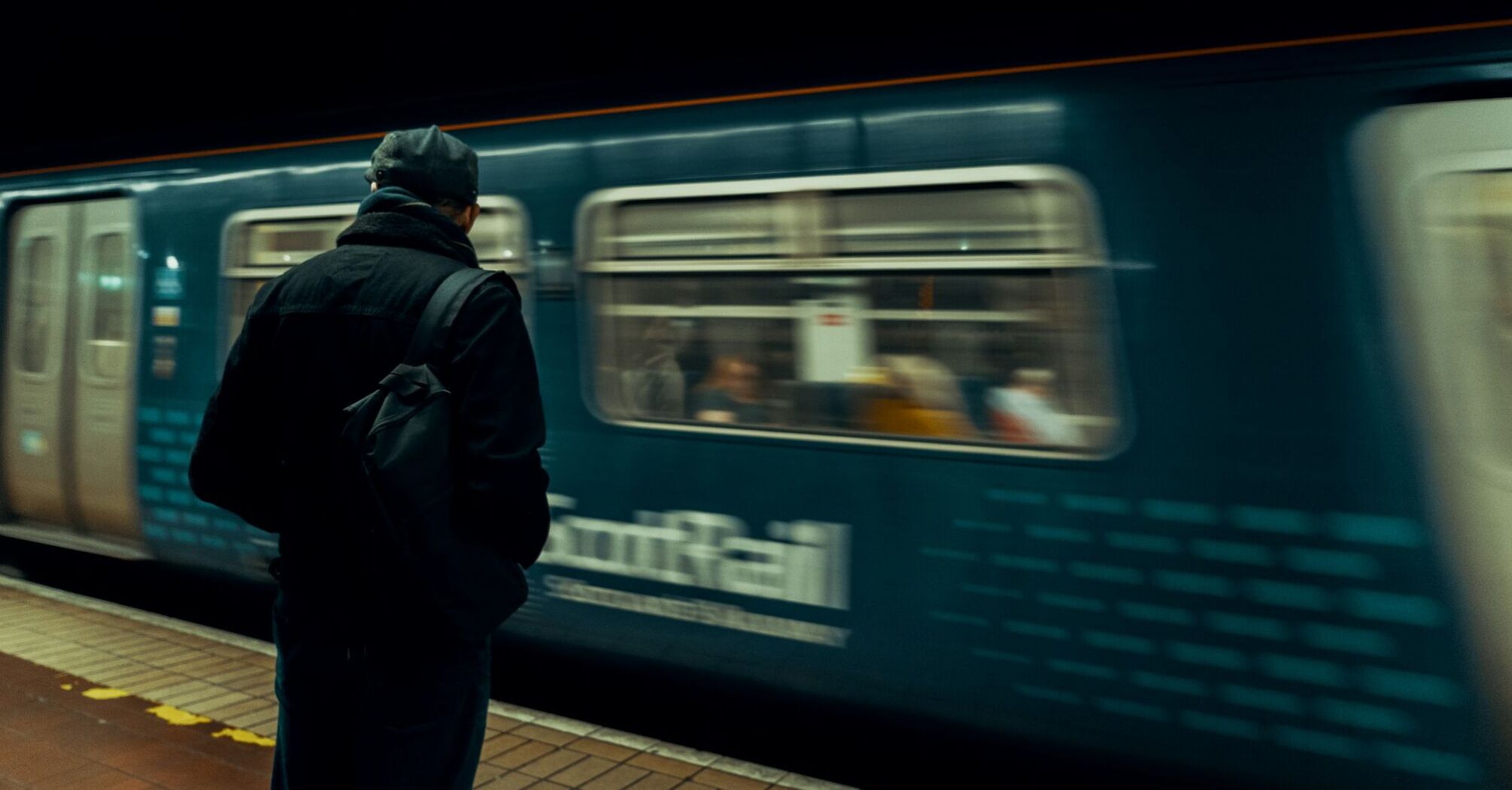 A person waits on the platform as a ScotRail train speeds past at an underground station