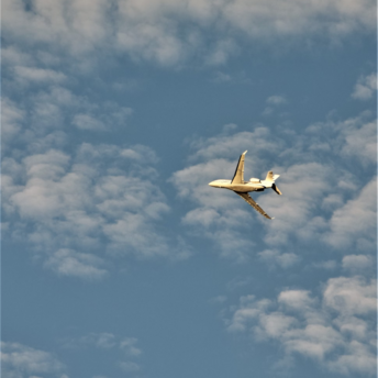 Private jet flying through a blue sky with scattered clouds