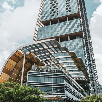 Modern glass high-rise JW Marriott hotel with a sleek architectural design under a blue sky with clouds