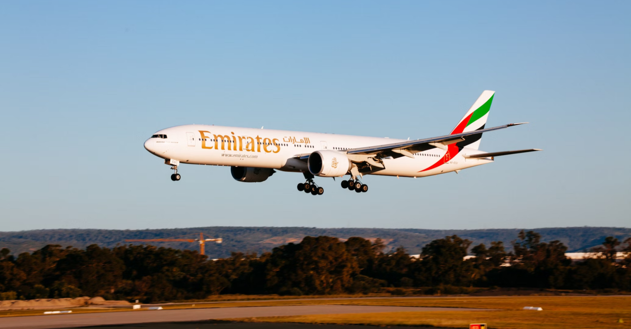 Emirates Boeing 777 aircraft landing at an airport during sunset