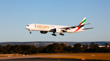 Emirates Boeing 777 aircraft landing at an airport during sunset