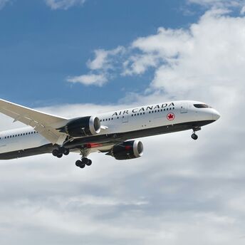 Air Canada aircraft in flight against a partly cloudy sky