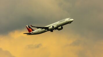 A Philippine Airlines aircraft ascending against a cloudy sky
