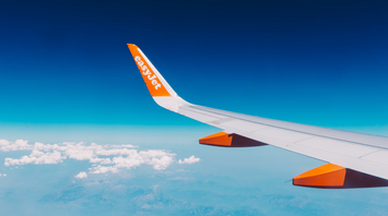 EasyJet airplane wing flying over a coastal landscape with clear skies