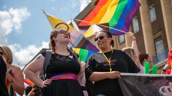 People celebrating Pride with rainbow and LGBTQIA+ flags at a UK summer event