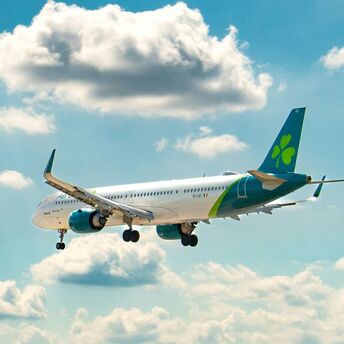 Aer Lingus aircraft flying through a partly cloudy sky