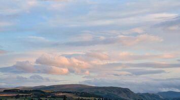 Rolling hills under a calm, cloud-filled sky at dusk in the UK countryside