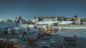 Lufthansa planes and ground vehicles at a busy German airport terminal