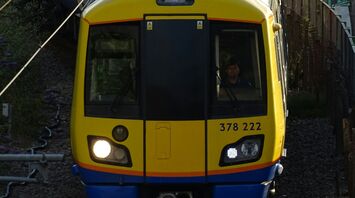 Front view of a yellow and blue passenger train approaching on curved tracks