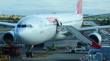 An Iberia aircraft at the gate with boarding stairs connected