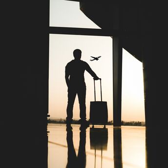 Traveler with suitcase watching airplane take off at airport terminal