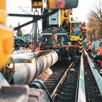 Rail workers operating heavy machinery to replace tracks during infrastructure upgrade