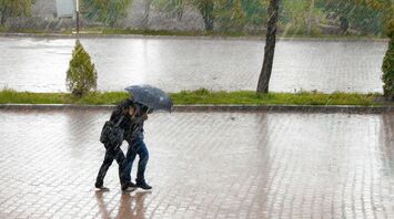 Two people walking with an umbrella during heavy rain on a flooded street